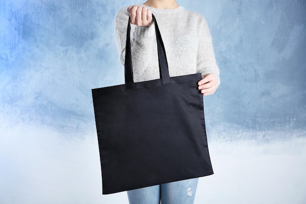 Young woman with shopping bag on color background