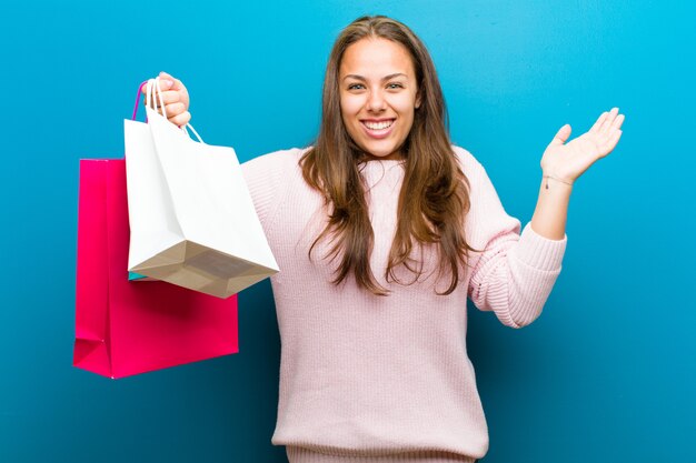 Young woman with shopping bags against blue background