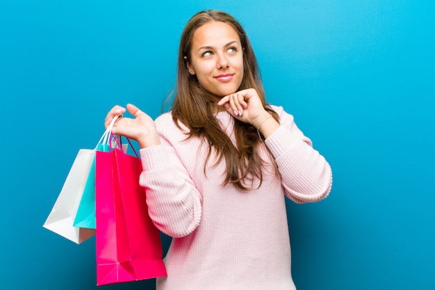 young woman with shopping bags against blue background