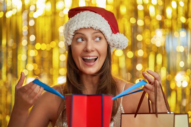 Young woman with shopping bags over gold background