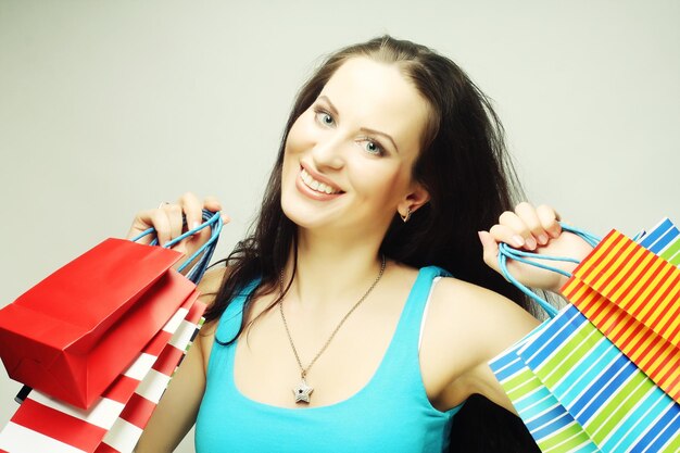 Young woman with shopping bags over gray background