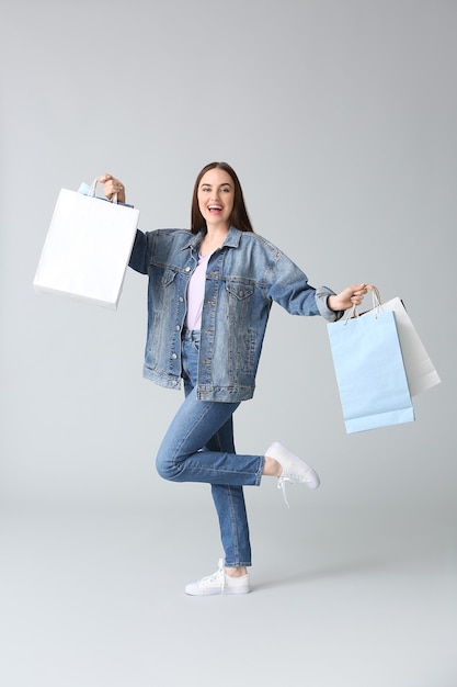 Young woman with shopping bags on grey background