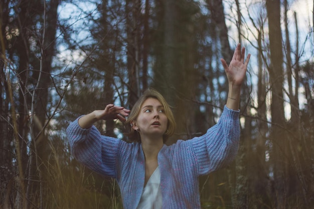 Foto giovane con i capelli corti che danza contro gli alberi nella foresta