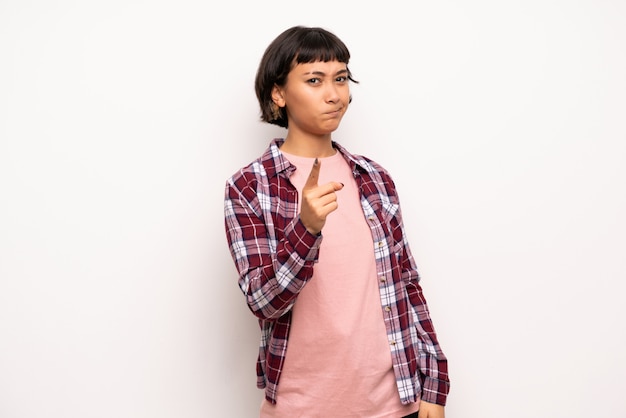 Young woman with short hair frustrated by a bad situation and pointing to the front