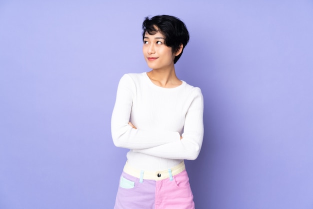 Young woman with short hair over purple looking to the side