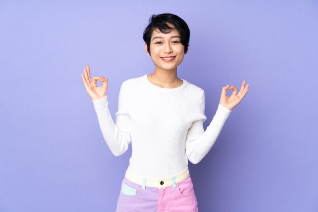 Young woman with short hair over purple in zen pose