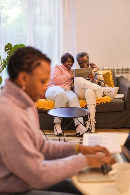 Young woman with short hair working remotely while taking care of her elderly parents Concept people care teleworking conciliation