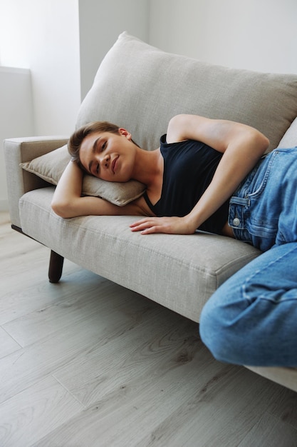 Young woman with short haircut hair having fun at home on the couch smile and happiness vacation at home natural posing without filters free copy space