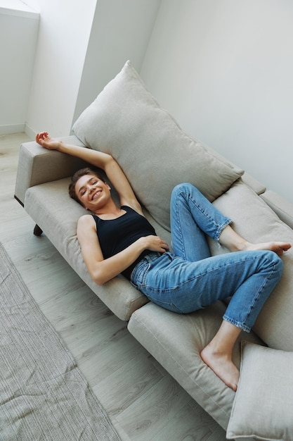 Young woman with short haircut hair having fun at home on the couch smile and happiness vacation at home natural posing without filters free copy space