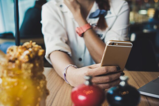 Foto giovane donna con lo smartphone in mano seduta in un caffè di strada