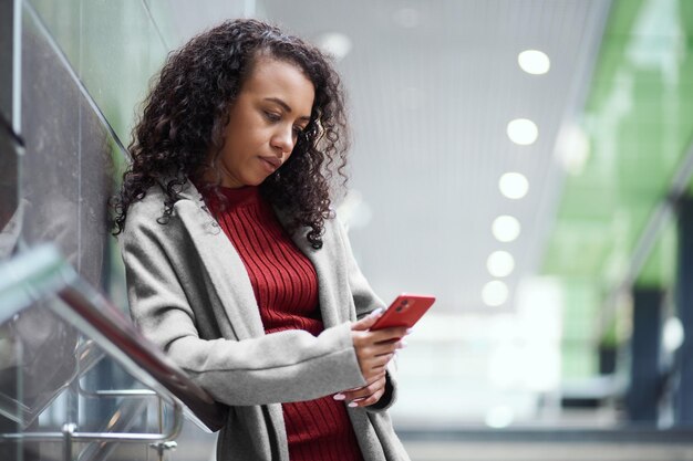 Young woman with a smartphone standing at a subway station