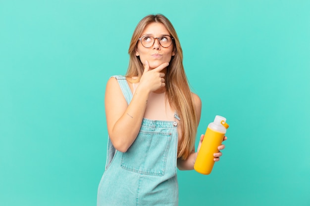 Young woman with a smoothy thinking, feeling doubtful and confused