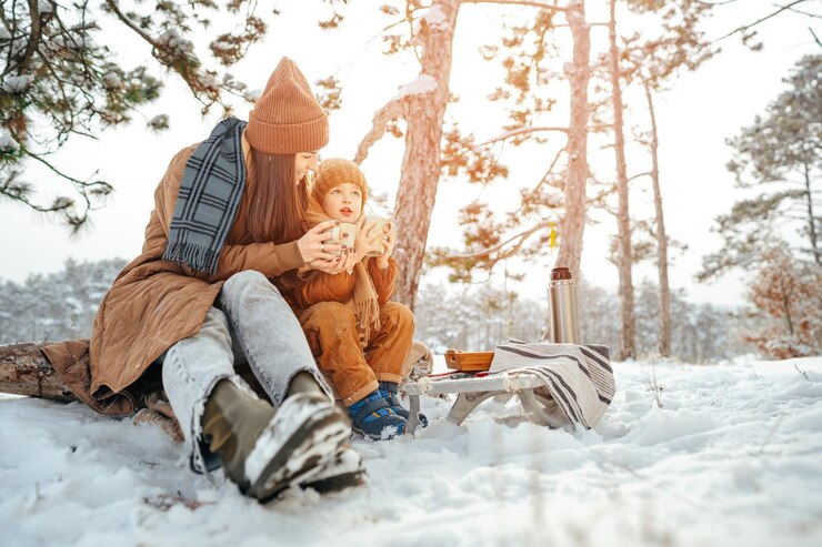 Photo young woman with a son in winter forest on a picnic drink hot tea