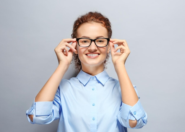 Young woman with spectacles on grey background