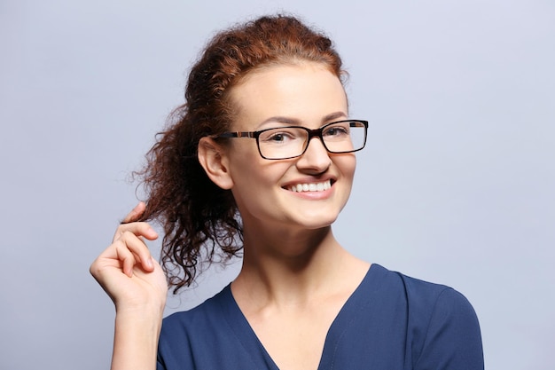 写真 灰色の背景に眼鏡をかけて若い女性