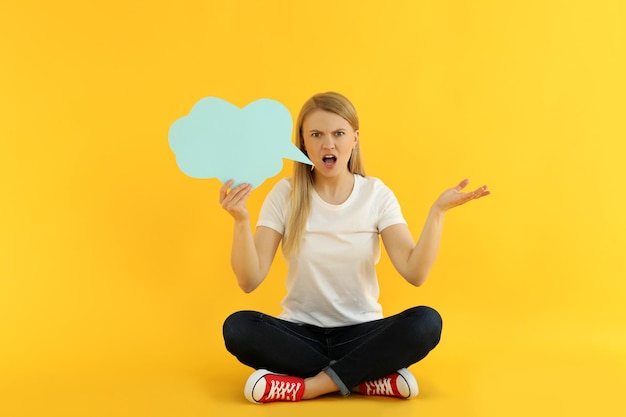 Young woman with speech bubble on yellow background