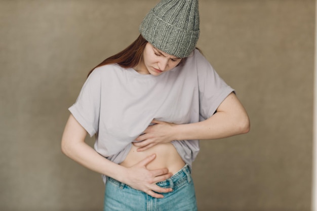 Young woman with stomach pain ache against brown background