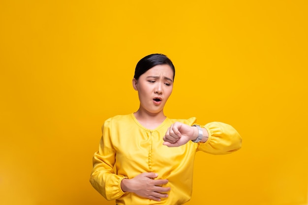 Young woman with stomachache against yellow background
