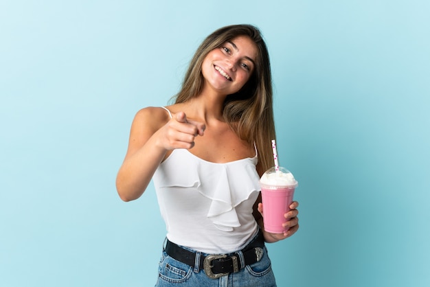 Giovane donna con il frappé della fragola isolato sulla parte anteriore indicante blu con l'espressione felice