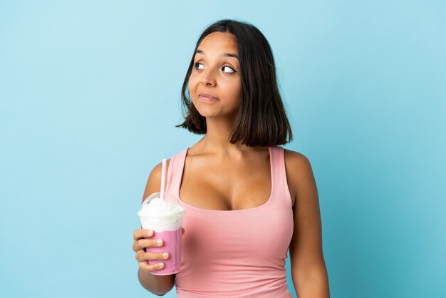 Молодая женщина с клубничным молочным коктейлем изолированы
