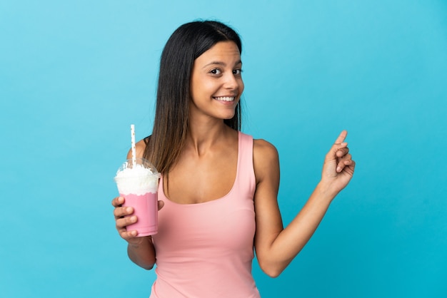 Young woman with strawberry milkshake pointing back