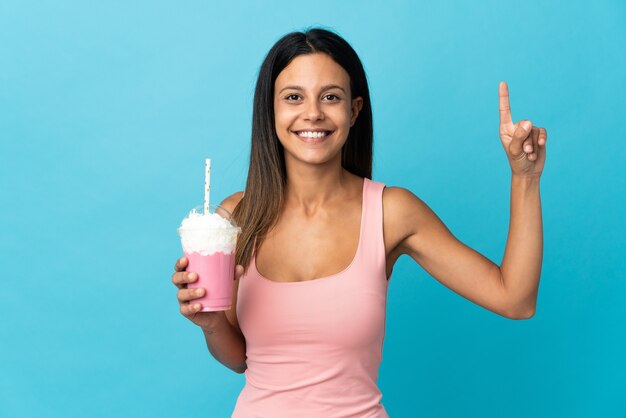 Young woman with strawberry milkshake pointing up a great idea