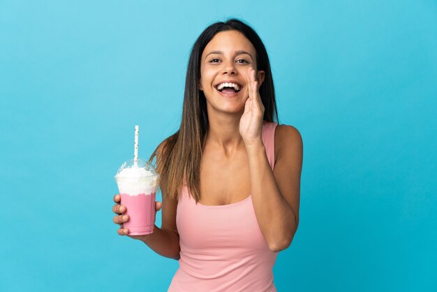 Young woman with strawberry milkshake shouting with mouth wide open