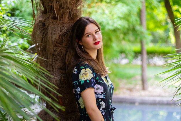 Young woman with stylish clothes posing in a paradisiacal park at sunset