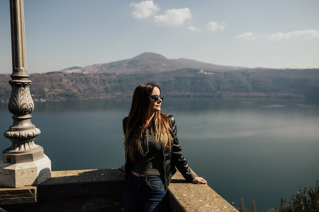 Young woman with sunglasses with lake and mountains behind