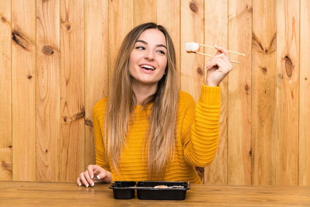 Young woman with sushi over wood background