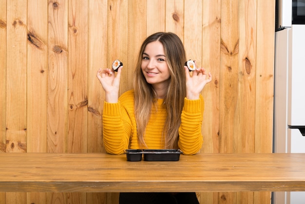 Young woman with sushi over wood wall