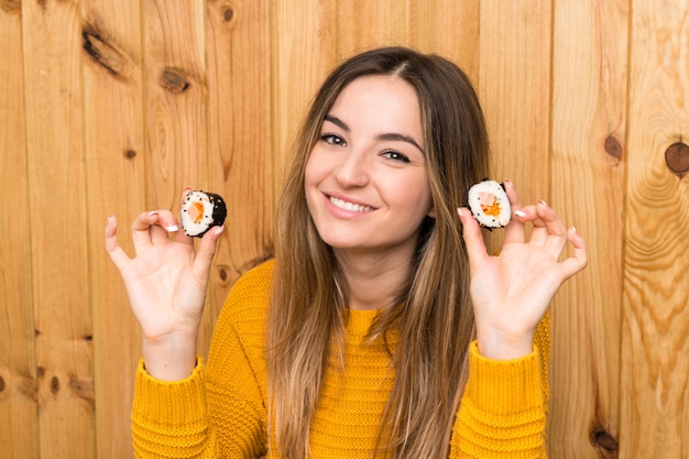 Young woman with sushi over wood 