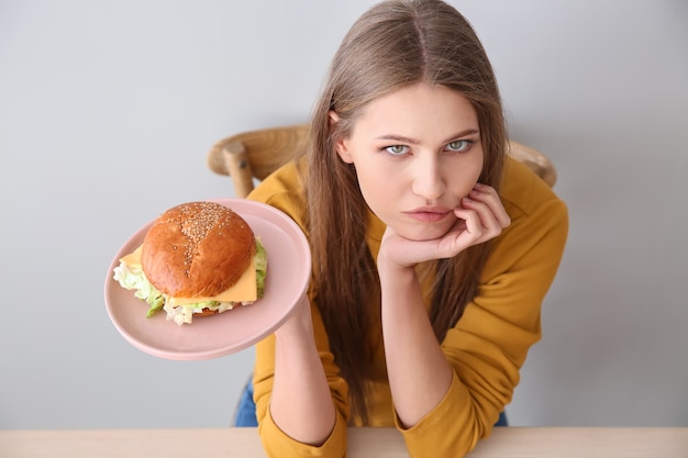 Foto giovane donna con gustosi hamburger al tavolo