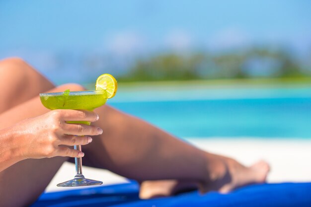 Young woman with tasty cocktail on white tropical beach