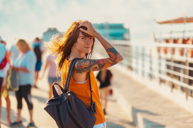 Young woman with tattoos wearing backpack turns back and smiling freedom and summer vacation