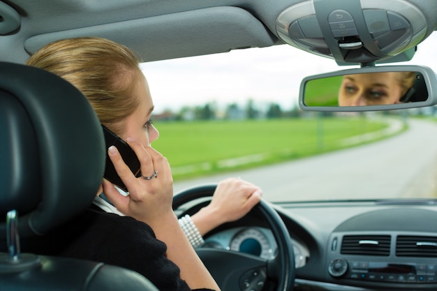 車の中で電話を持つ若い女性