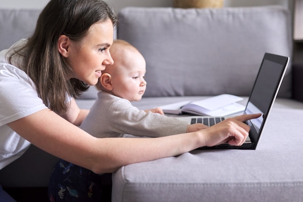 Young woman with toddler making video call, video conference using laptop at home. Remote work, online communication with colleagues, clients. Technology, distance lifestyle concept