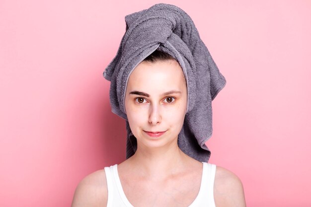 Фото Молодая женщина с полотенцем на голове красит себе брови. концептуальный спа-день дома и на карантине