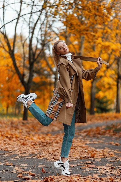 young woman with a trendy hairstyle in an elegant coat poses outdoors in a park