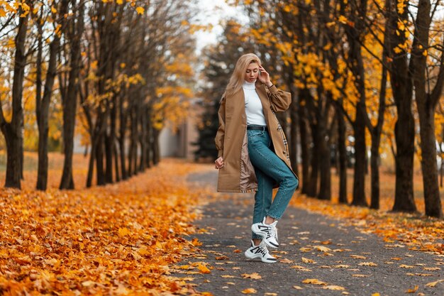 young woman with a trendy hairstyle in an elegant coat poses outdoors in a park