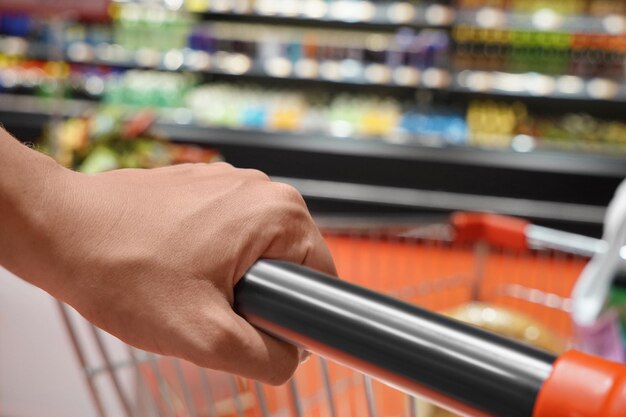 Foto giovane donna con carrello che sceglie i prodotti nel supermercato