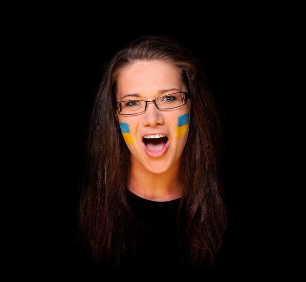 a young woman with Ukrainian flags on cheeks standing over black