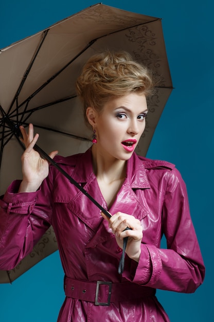 Young woman with umbrella on blue