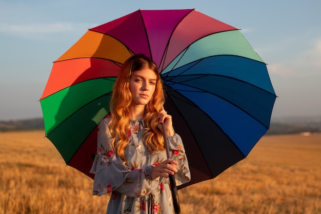 Young woman with umbrella in the field