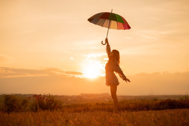 Young woman with umbrella in the field