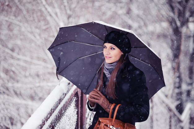 降雪の傘を持つ若い女性