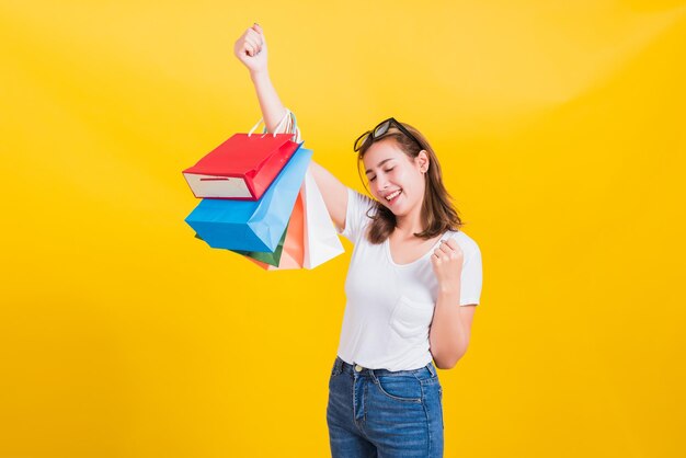 Young woman with umbrella standing against yellow background