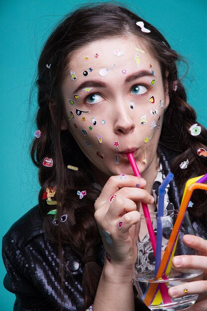 Photo young woman with various stickers on face and hands having drink