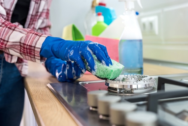 Giovane donna con detersivo liquido e straccio lava e pulisce in cucina. concetto di pulizia.