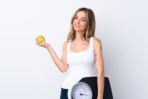 Young woman with weighing machine and with an apple